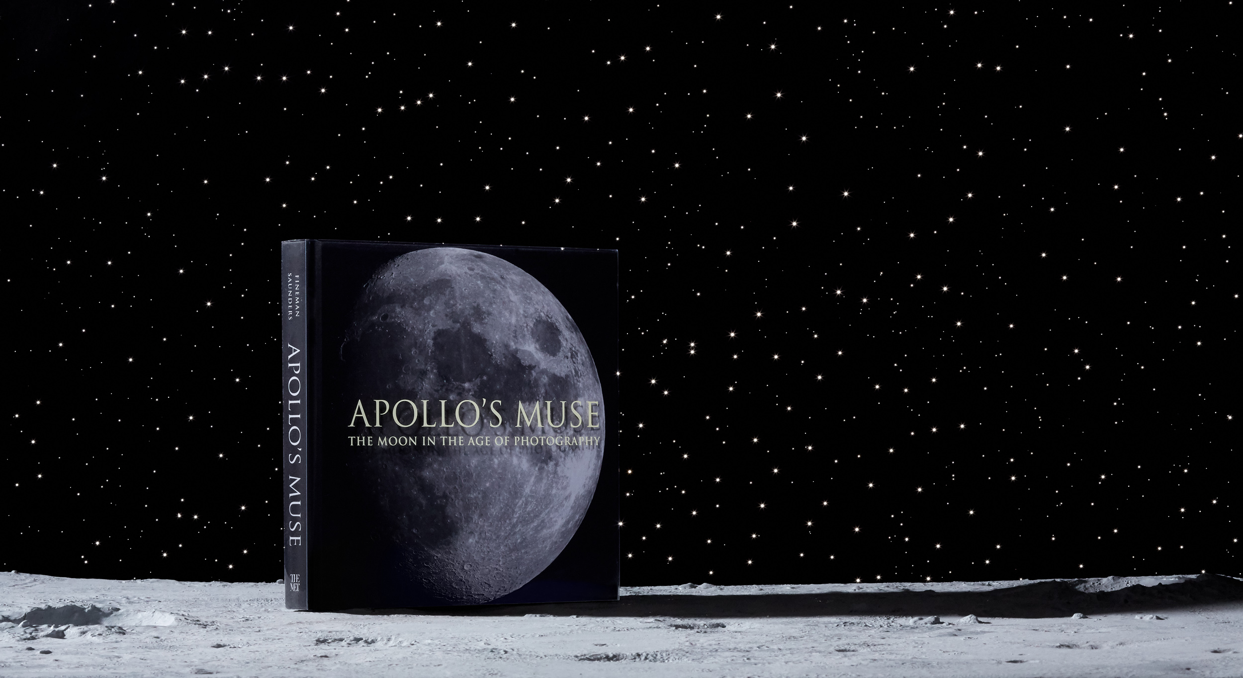 marketing still life photograph of the Apollo's Muse exhibition catalog book on the moon with a star-field background