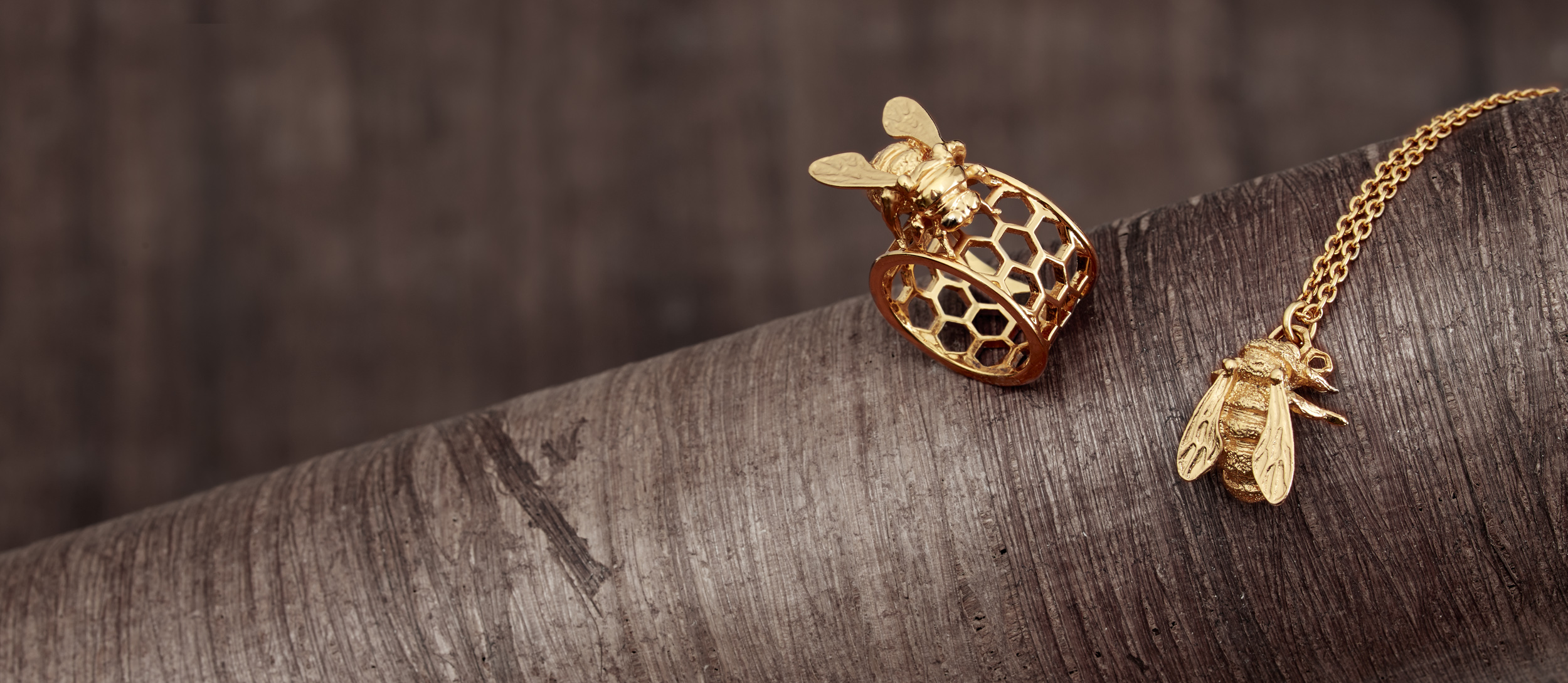 gold bee ring and gold bee necklace on wood branch