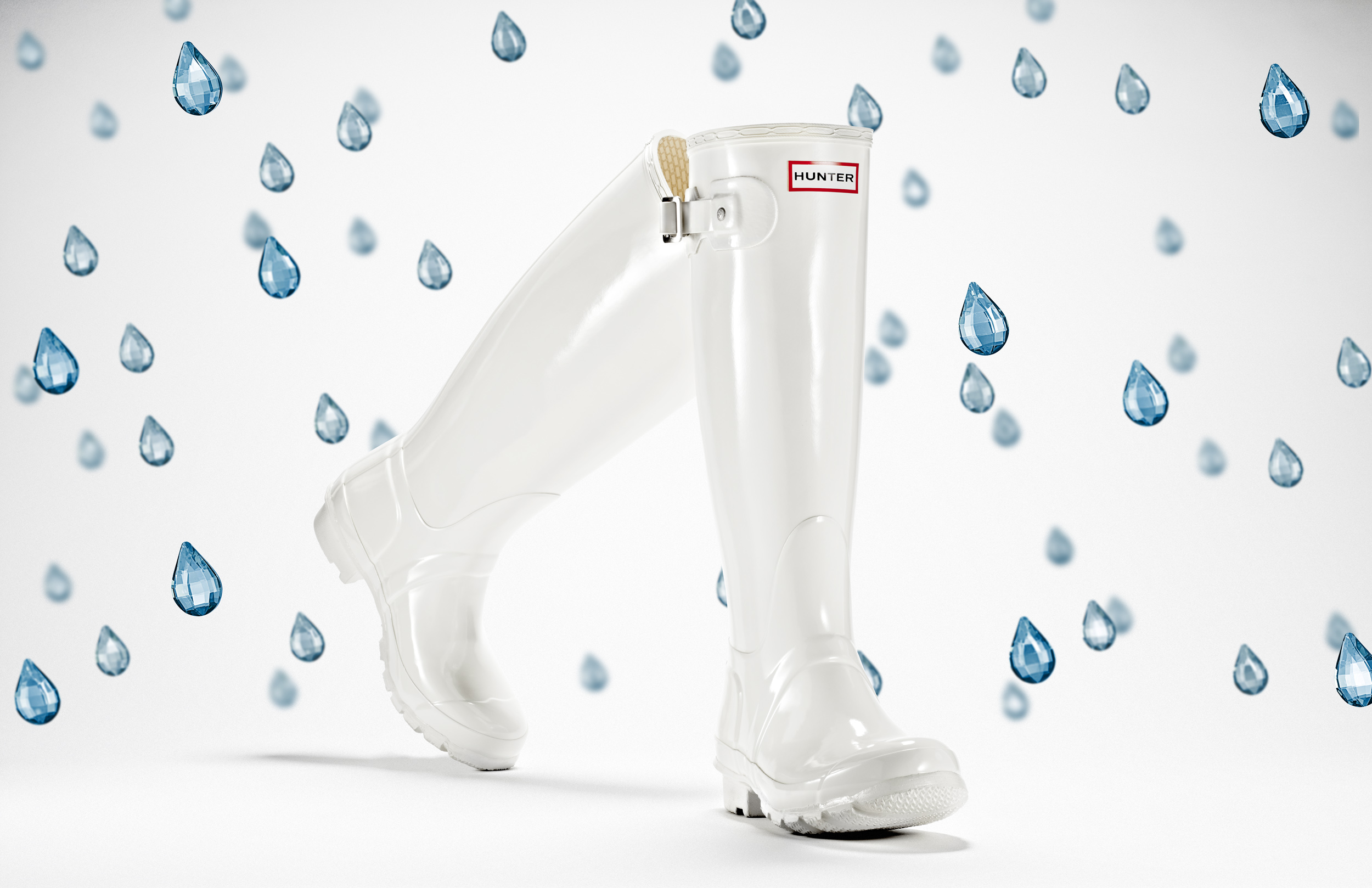 advertising still life photograph of white hunter boots surrounded by blue jewel raindrops