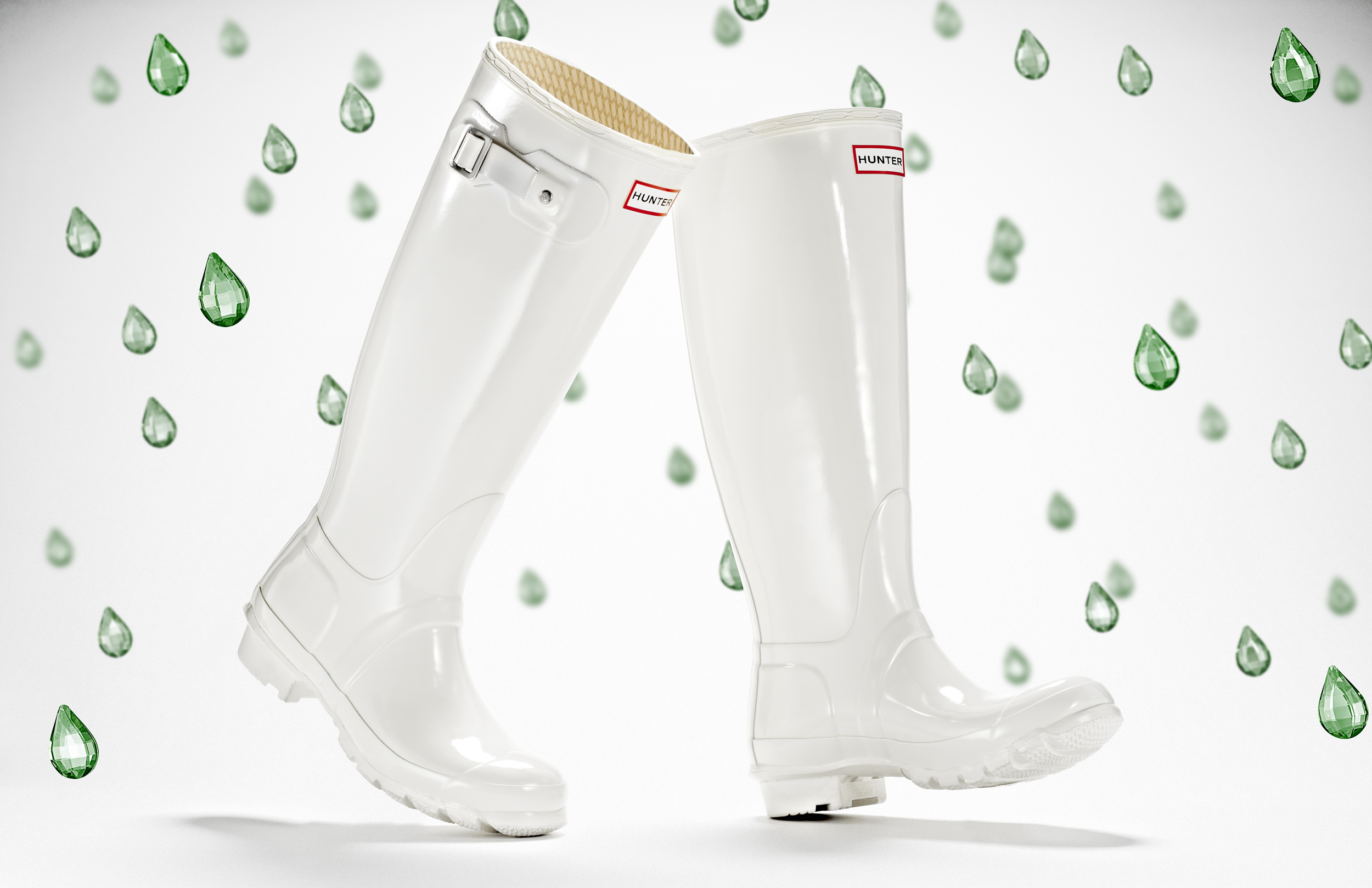 advertising still life photograph of white hunter boots surrounded by green jewel raindrops