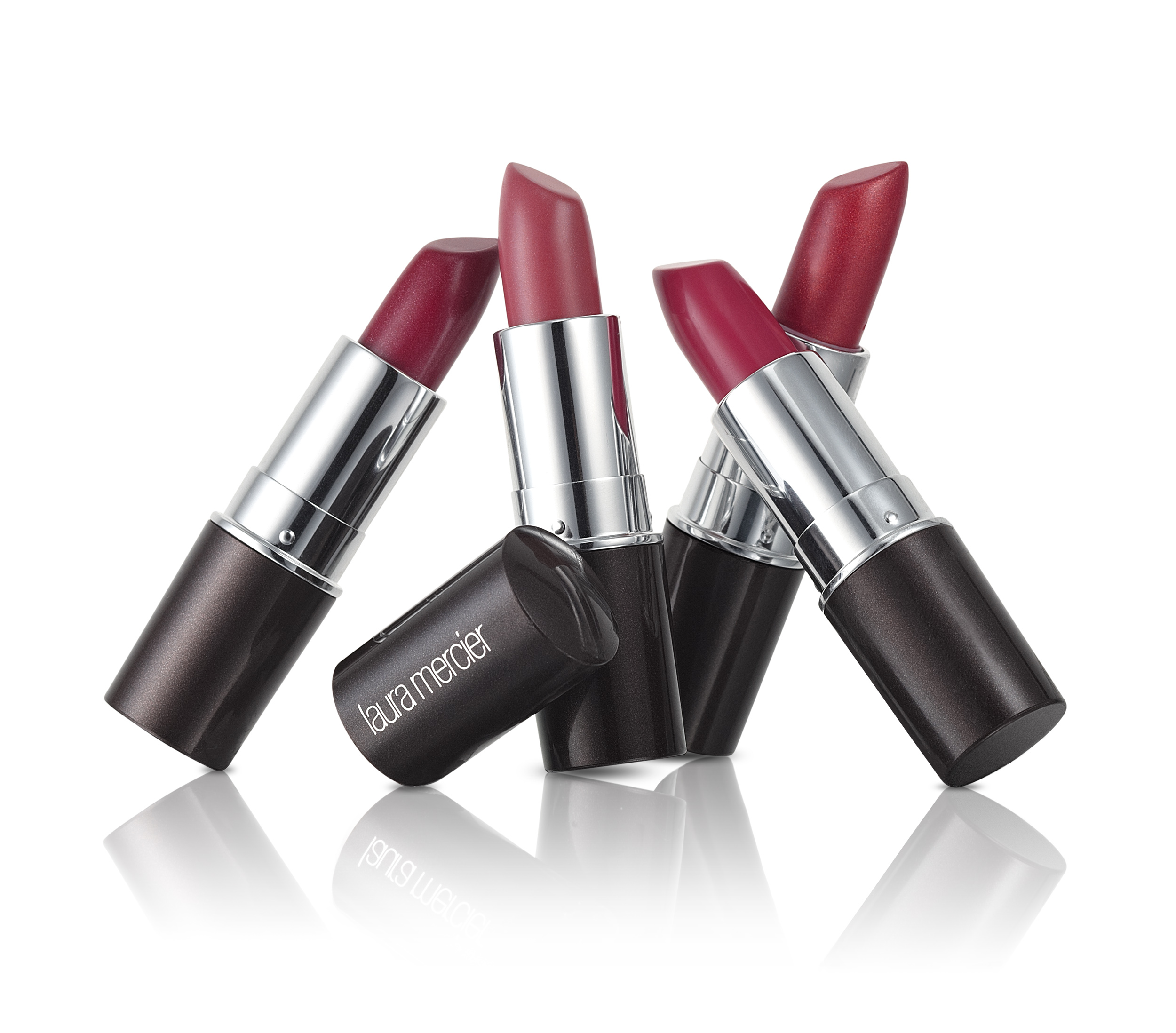 e-commerce product photograph of four red and pink lipsticks in a dynamic group composition on white with a reflection