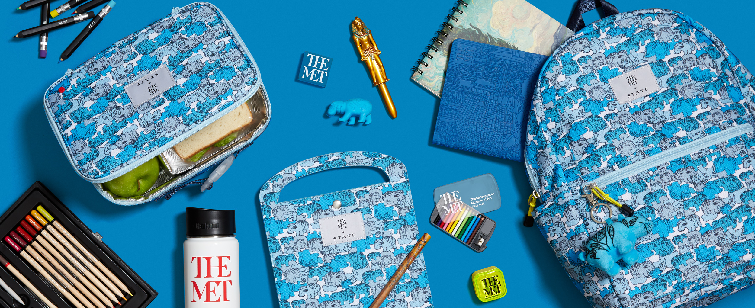 e-commerce header of the Met x State collaboration with hippo backpack, lunch box, art folio, and supplies on blue background